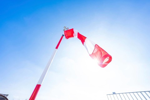 A red and white windsock under a blue sky and bright sun on an airfield, heliport of the new Calw