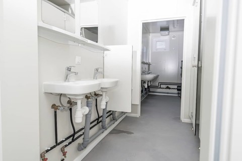 Bright bathroom with elongated layout and several washbasins, refugee accommodation Beermiß,