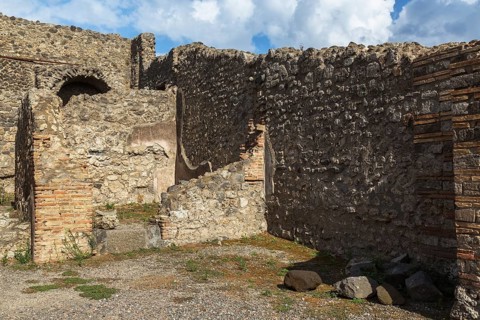 Remnants of old terracotta brick and stone wall structures with arched opening at the ancient ruins