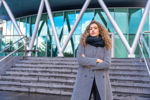 Portrait of a proud young woman standing in the street with warm clothes