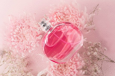 A sophisticated pink perfume bottle elegantly placed on a soft surface adorned with pink flowers