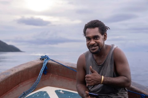 A smiling native man from Kri Island in the Raja Ampat Archipelago of West Papua, Indonesia, sits