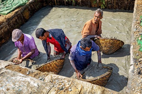 Four men stand in a water-filled area, working with baskets, the sapphire and gemstone mines at
