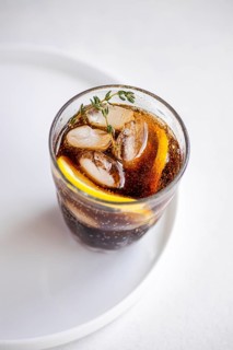 A beautifully presented gin cocktail served in a clear glass with cola drink, garnished with fresh