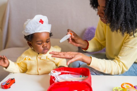 African mother and daughter playing doctors dressed like nurses at home