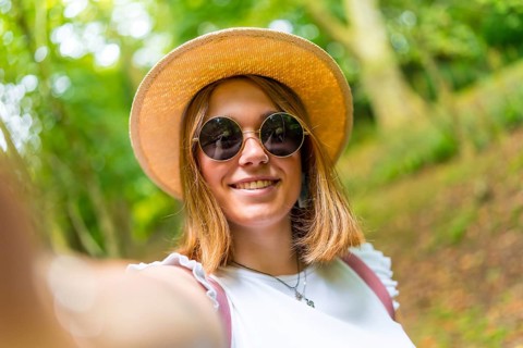 Personal point of view of a caucasian happy young woman taking a selfie while hiking in the forest