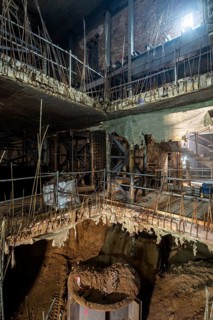 View of an ongoing construction site featuring exposed rebar, concrete floors, and temporary