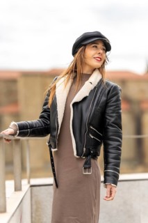 Fashionable woman posing in an urban environment, wearing a black leather jacket with a sheepskin