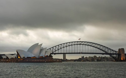 Moody sky over Sydney with the famed Opera House and Harbour Bridge in view. The still water