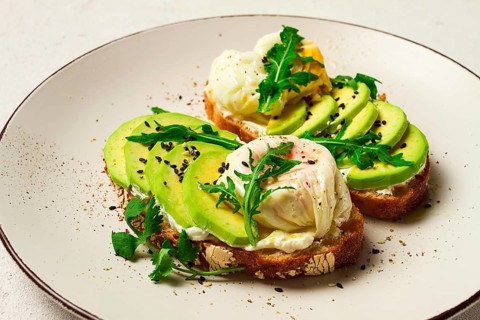 Sandwich with cream cheese, sliced avocado and boiled egg, arugula, on grainy bread, homemade,