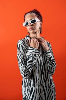 A fashion model poses confidently in a zebra-patterned blouse, adorned with modern accessories,