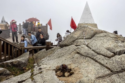 People on a viewing platform with triangular stone markings on rocks in foggy surroundings, The