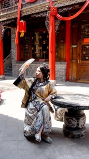 A woman dressed in elaborate Qing Dynasty attire sits gracefully outdoors in historic Pingyao,