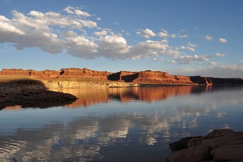 Perfect reflection of a vast rocky landscape with clouds in calm waters, Lake Powell, Arizona, USA