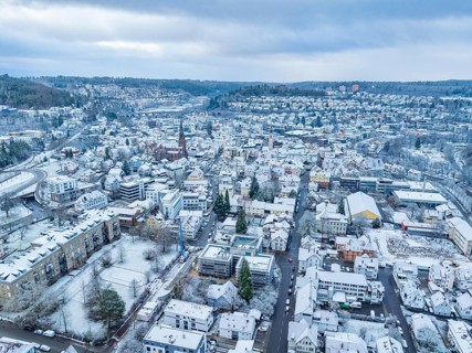 Aerial view of a snowy town with houses and mountains in the background, peaceful winter