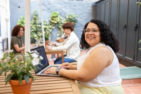 Diverse group enjoying a summer coworking session at an outdoor patio. Smiling individuals work on