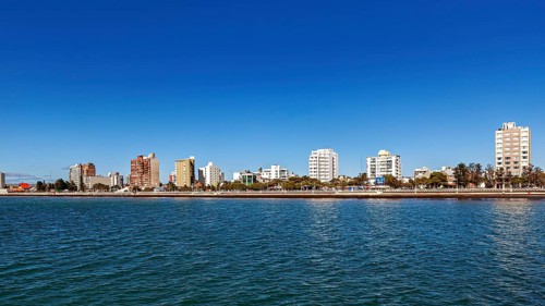 Skyline of a coastal town with tall buildings on a sunny day and calm water, the city of Puerto