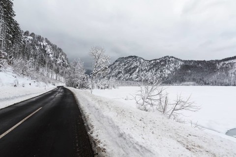 Snow covered Lake Almsee which is partly frozen and snow covered. Snow on the trees and mountains