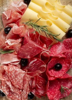 Assorted meat, appetizer, prosciutto, salami and ham, with maasdam cheese and olives, on a wooden