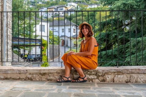 Portrait of a sitting tourist woman looking from a viewpoint at the city of Gjirokaster or