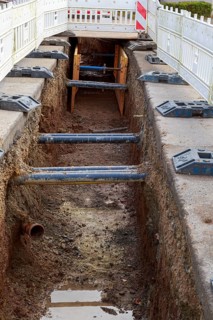 Excavation pit with safety barriers, wooden supports and earthworks along the road