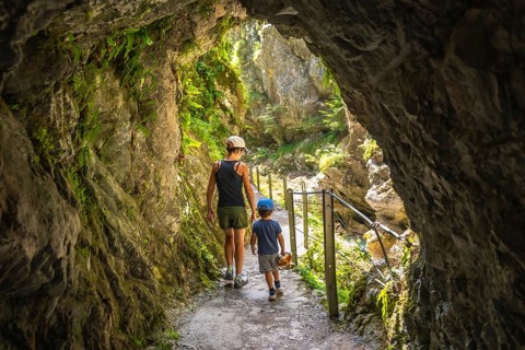 Mother and son walking through a narrow passage carved into the rock face at tolmin gorge in