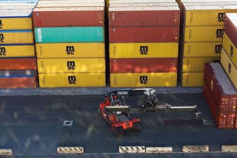 Stacked MSC, DONGFANG metal box shipping containers and Kone Cranes container handler on dock in La