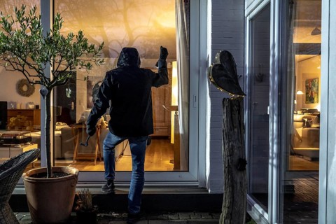 Symbolic image of a burglary, perpetrator spies on a flat from the garden side