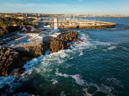 Aerial view of Santa Marta lighthouse and Cascais marina with moored yacht boats with Cascais