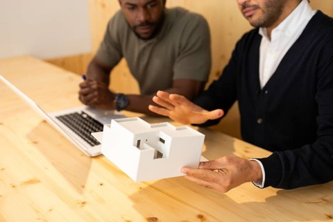 Two professionals in a modern coworking space in Barcelona discuss architectural concepts using a