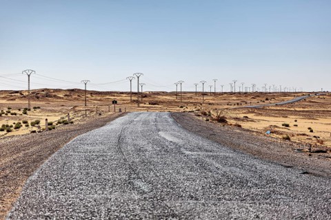 Long road through the desert with numerous electricity pylons stretching to the horizon, By car