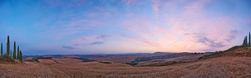 Typical Tuscan landscape in Crete Senesi with hills, trees, fields, farmhouses and cypresses at