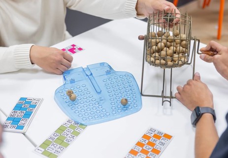 A group of people engage in leisure activities, playing games on a table. This setting promotes