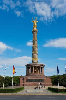 The Victory Column in Berlin, with golden figure under a clear sky, some tourists can be seen,