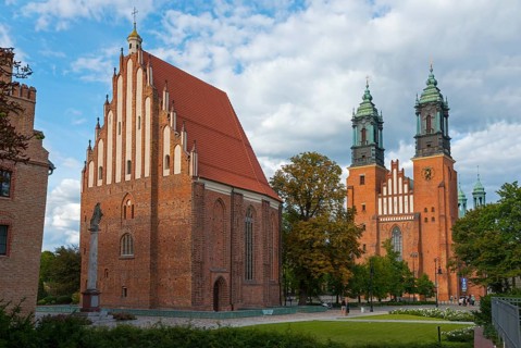A Gothic church building with red brick facades and towers under a slightly cloudy sky, Church of