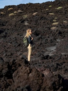 A woman explores the rugged volcanic terrain of Timanfaya National Park in Lanzarote, Canary