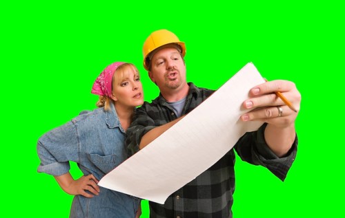 Contractor in hard hat discussing plans with woman over A green screen