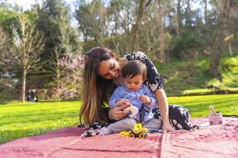 Mother and son enjoying quality time together, playing with toys on a blanket in a vibrant park