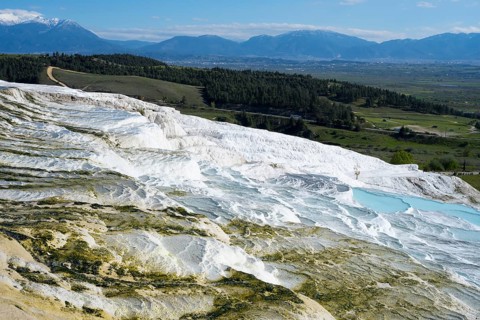White terraces and water basins with mountain views in the background, sinter terraces, lime sinter