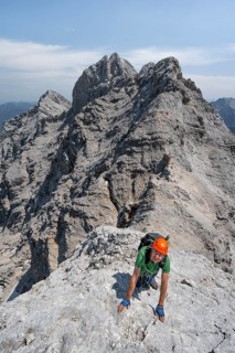 Mountaineer with helmet climbing on the rock, on a narrow rocky ridge, crossing the Jubiläumsgrat,