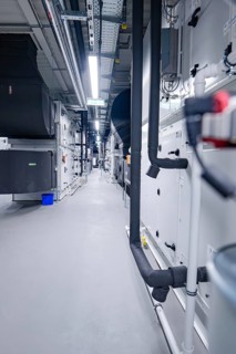 Aisle of an industrial ventilation system with visible pipes and machines in neutral colors,