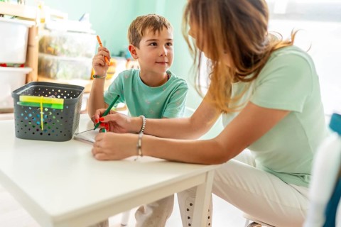 Side view close-up of a mom and school boy spending time together coloring at home