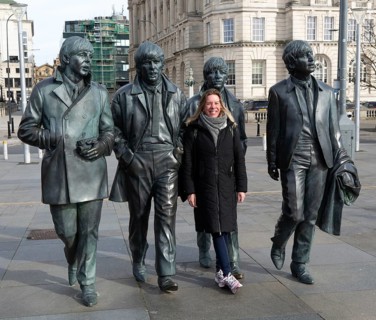 Woman standing next to The Beatles statues sculpture by Anthony Edwards, Pier Head, Liverpool,