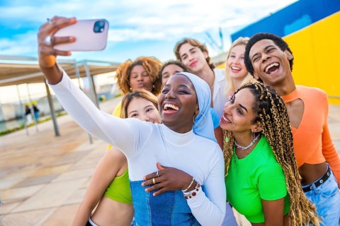 Happy muslim african woman taking a selfie while laughing with friends