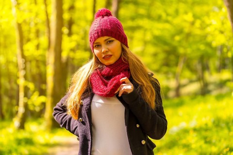 Latin girl with a black jacket, scarf and red woolen hat enjoying in an autumn park, portrait