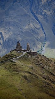 Gergeti church on a hill surrounded by mountains and gloomy atmosphere, Stepantsminda, Caucasus,