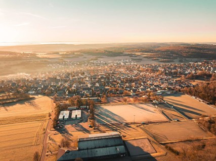 Sweeping view of a small town surrounded by fields and forests at sunrise, Gechingen, Heckengäu