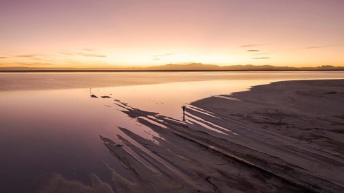 A solo traveler at a mesmerizing sunset in Salinas Grandes, Salta, Argentina, where the vast salt