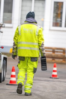Rear view of a worker in warning clothing on a road with traffic cones, Wend Glasfasermontage