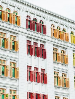 Vibrant red, yellow, and green window shutters contrast against the crisp white facade of a